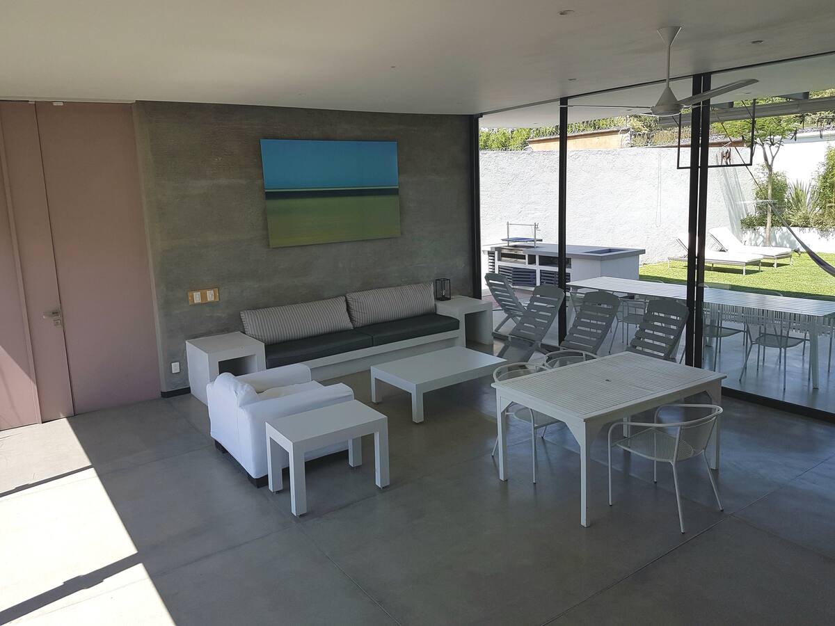 Terraza cubierta con salas y comedor abierta al jardín